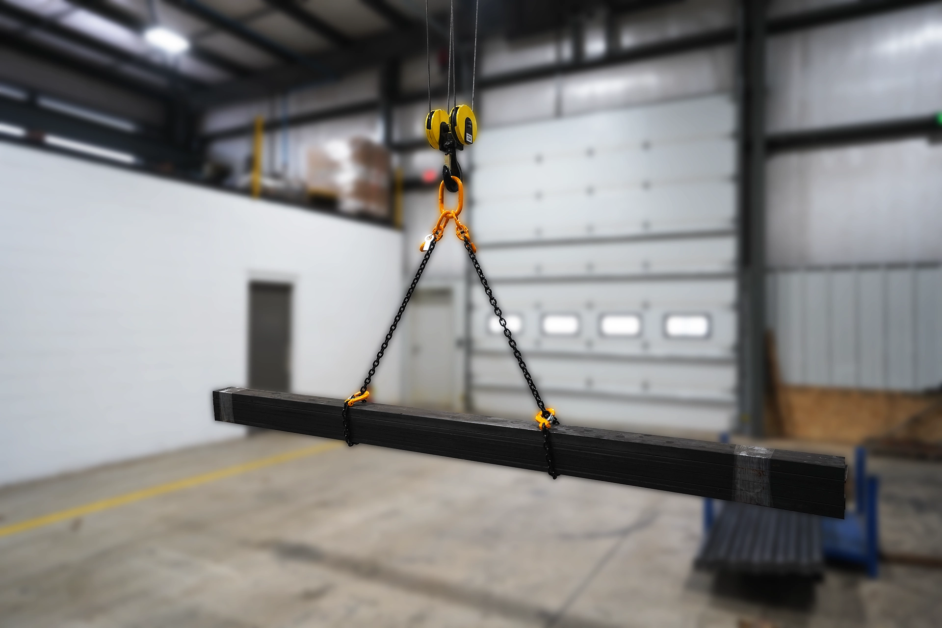 two leg chain sling lifting a load of tubular steel